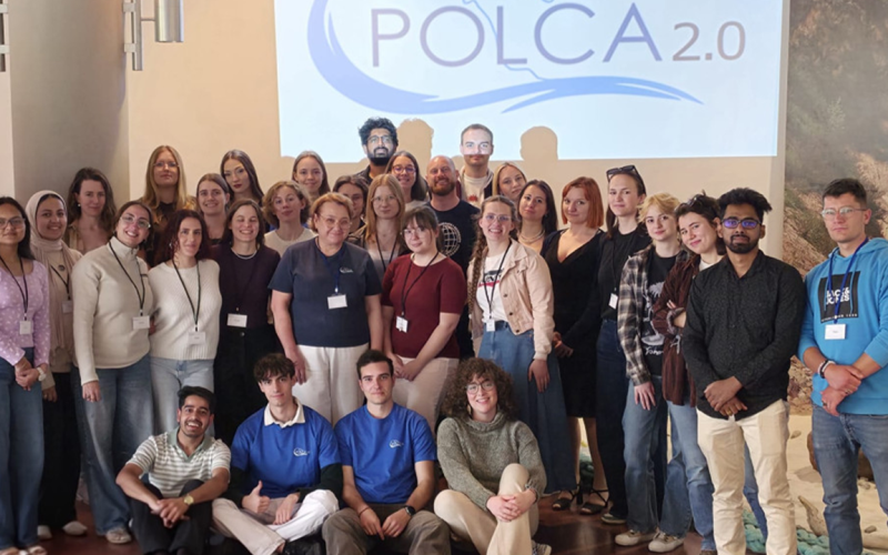 Fotografia grupowa uczestników na tle banneru POLCA 2.0